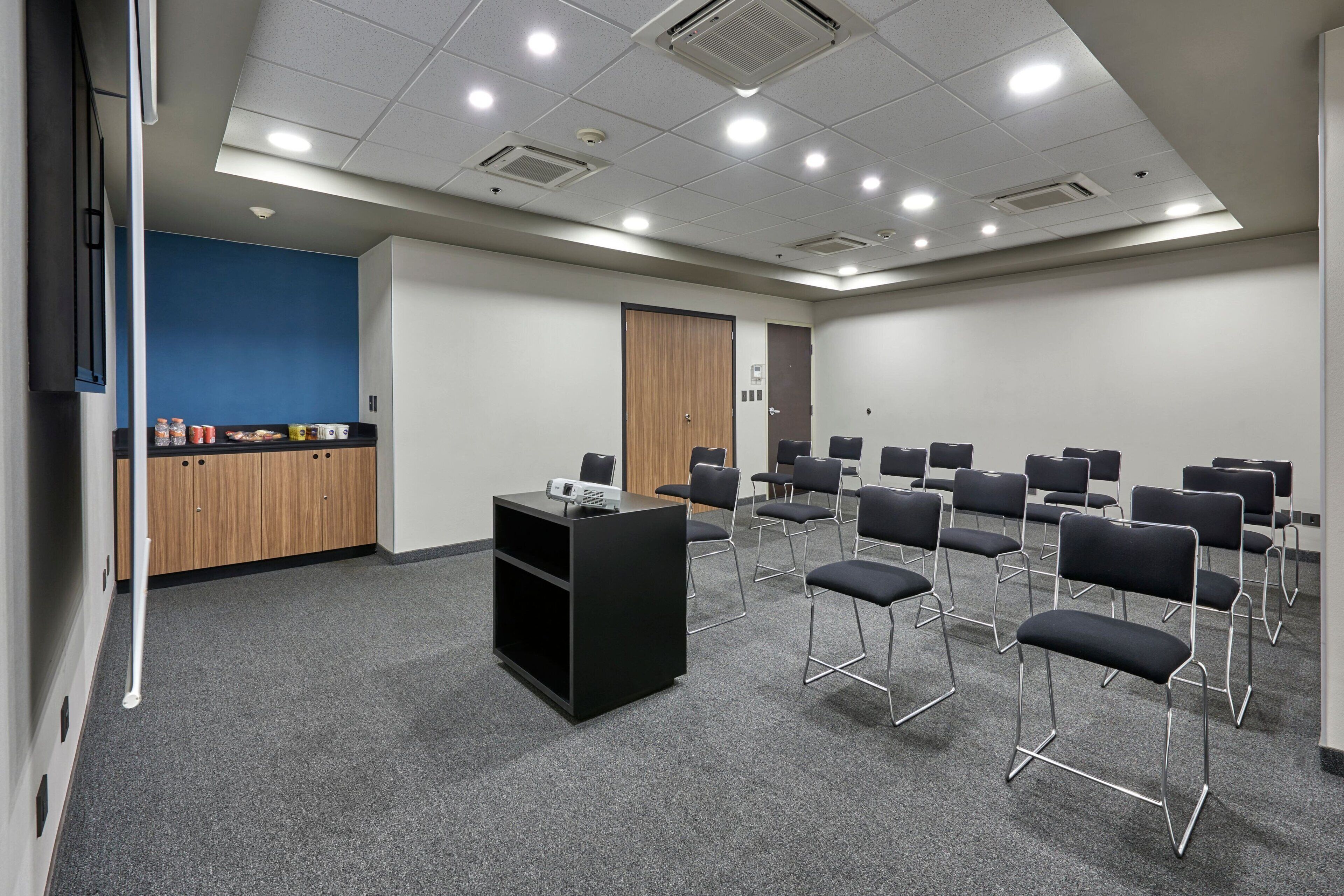 A conference room with a black podium, multiple chairs, and a blue accent wall.