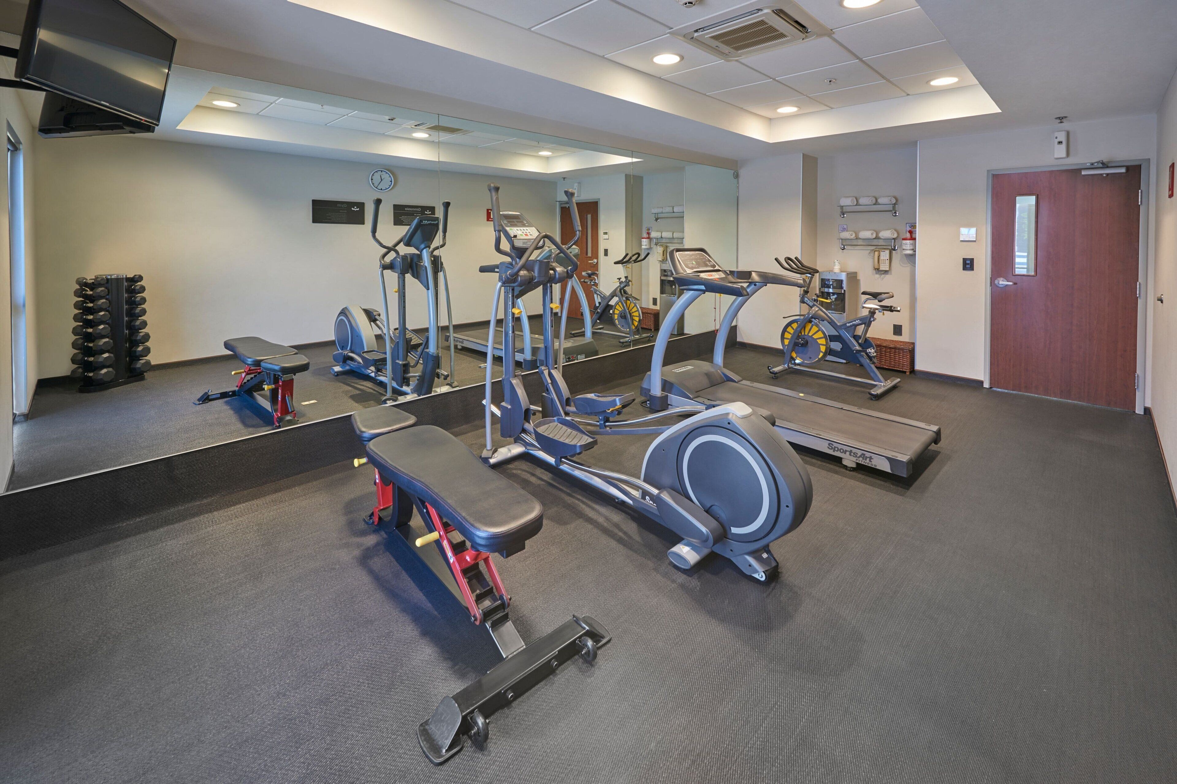 A gym with various exercise equipment, a mirror, and a door.