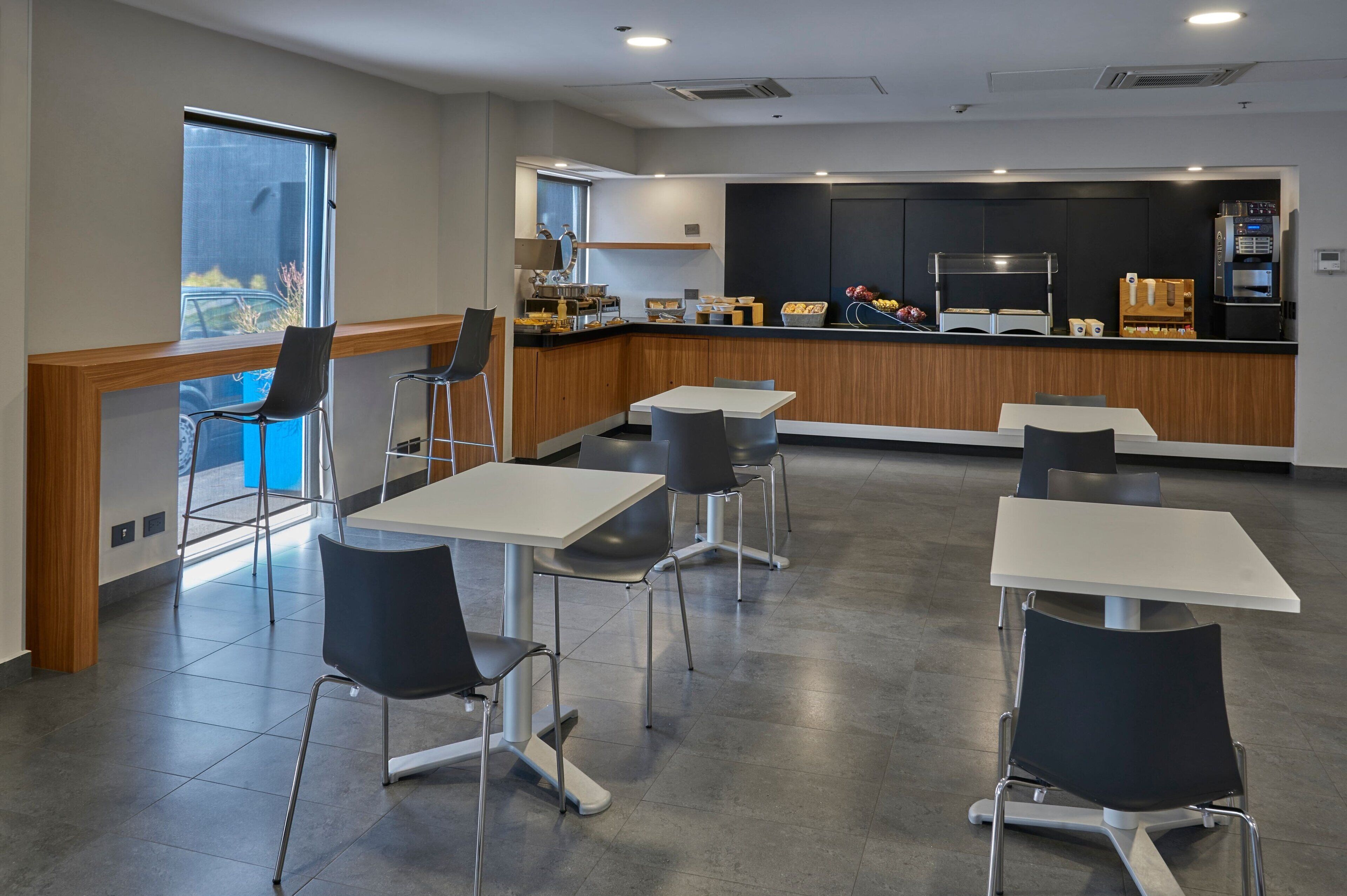 A modern restaurant with a counter, seating area, and kitchen.