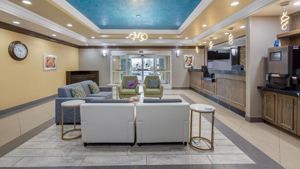 Un hall de hotel con un conjunto de sofás, un reloj, una recepción y una zona de cocina.