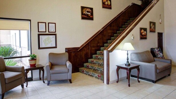 Una sala de estar con una escalera, un sofá, una silla, una mesa y una lámpara.