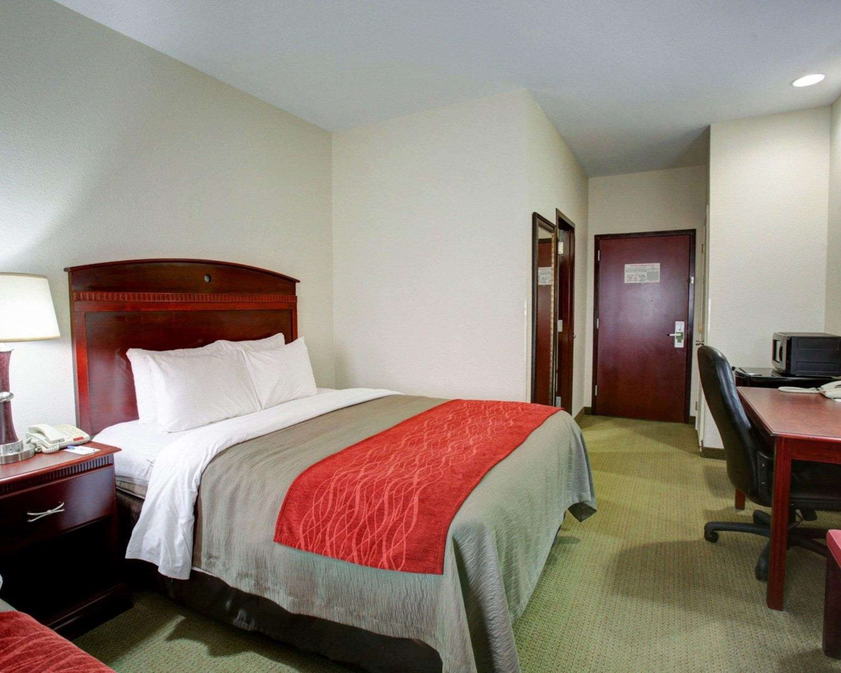 Une chambre d’hôtel équipée d’un lit, d’un bureau, d’une chaise, d’une lampe et d’un téléphone.