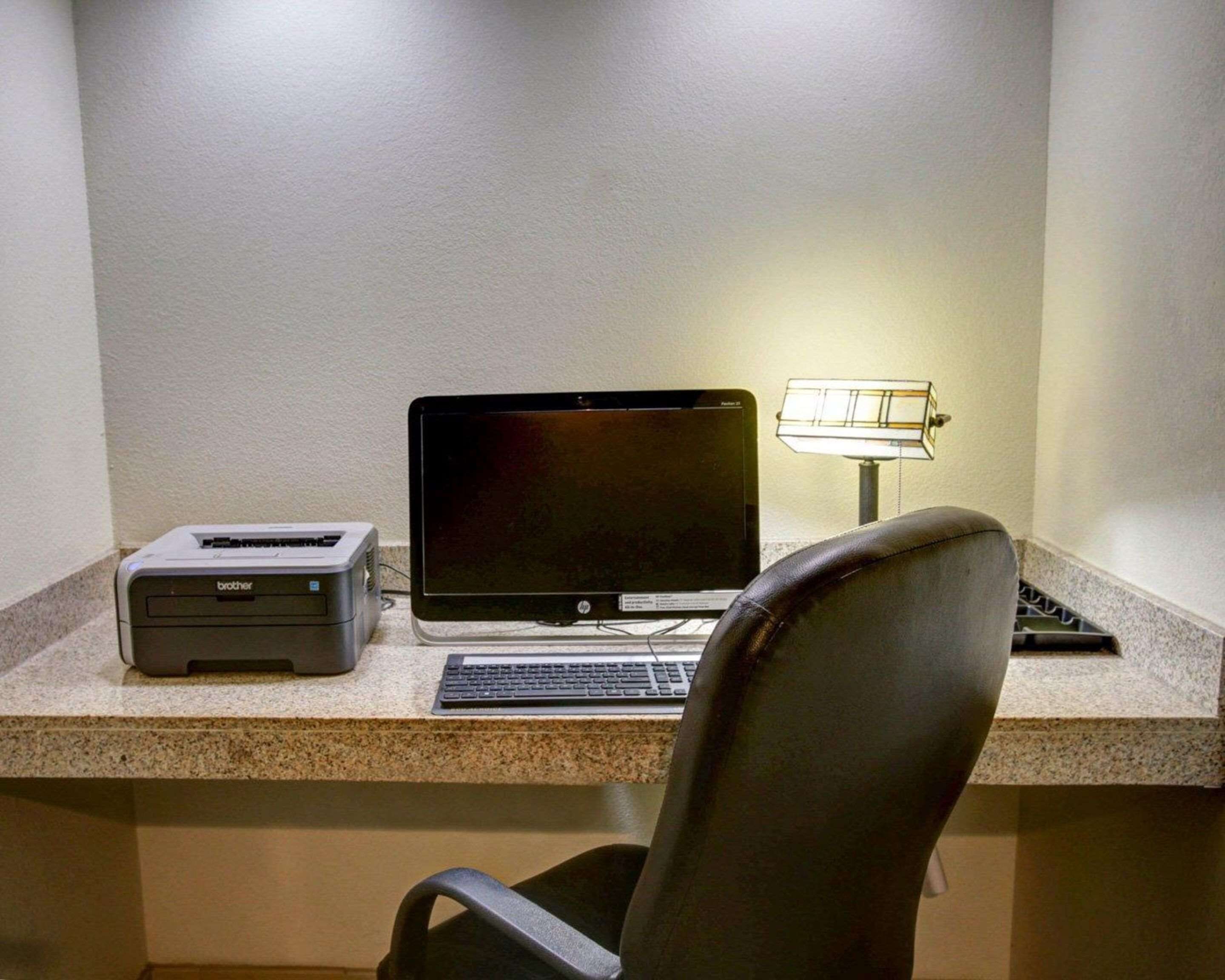 A desk with a Brother printer, an HP monitor, a keyboard, and a chair.
