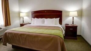Habitación de hotel con una cama grande, dos mesitas de noche con lámparas, un teléfono y una ventana con cortinas.