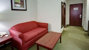 Una habitación pequeña con un sofá rojo, una mesa de madera y un cuadro en la pared.