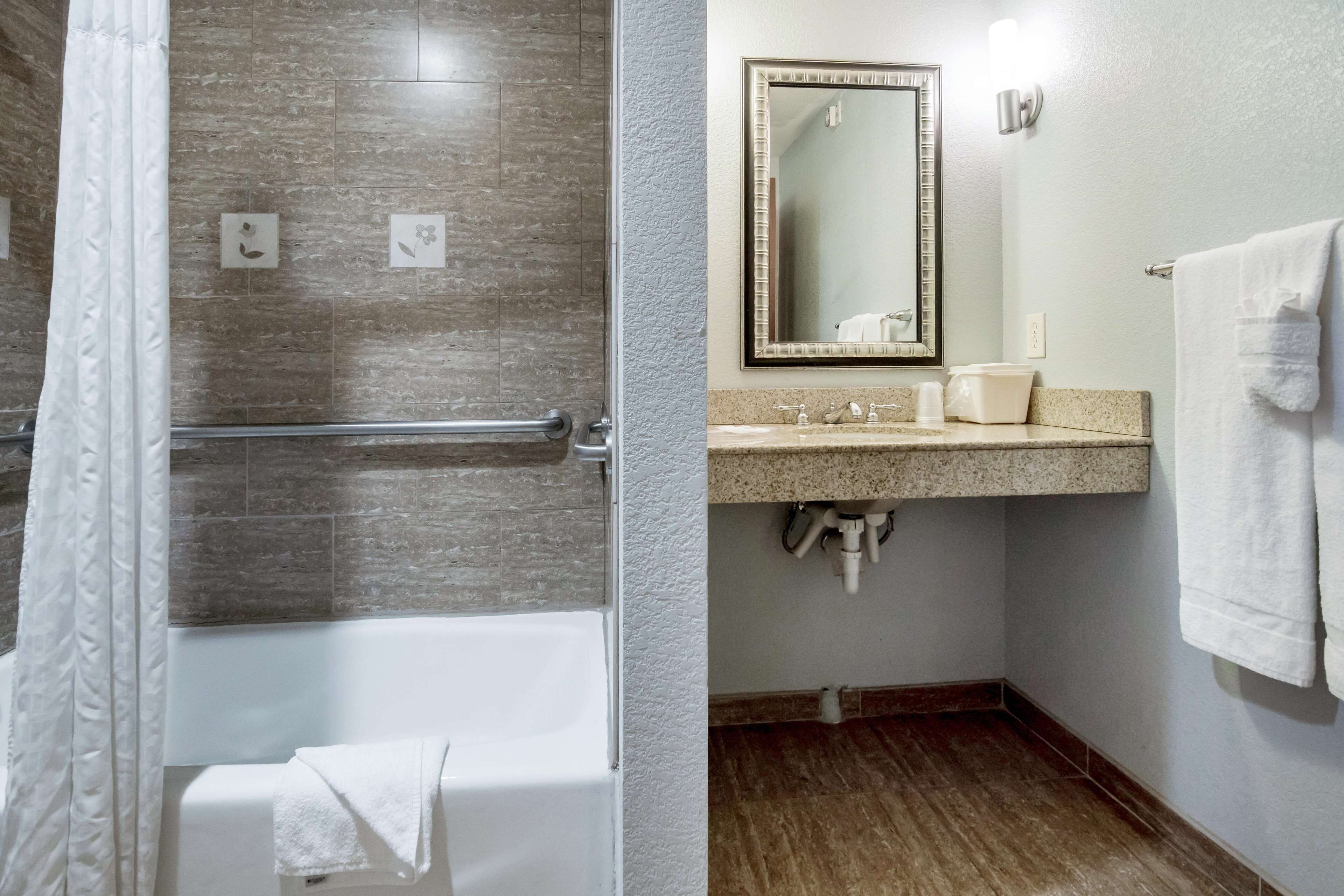 Un baño con ducha, bañera, lavamanos con espejo y toallero.