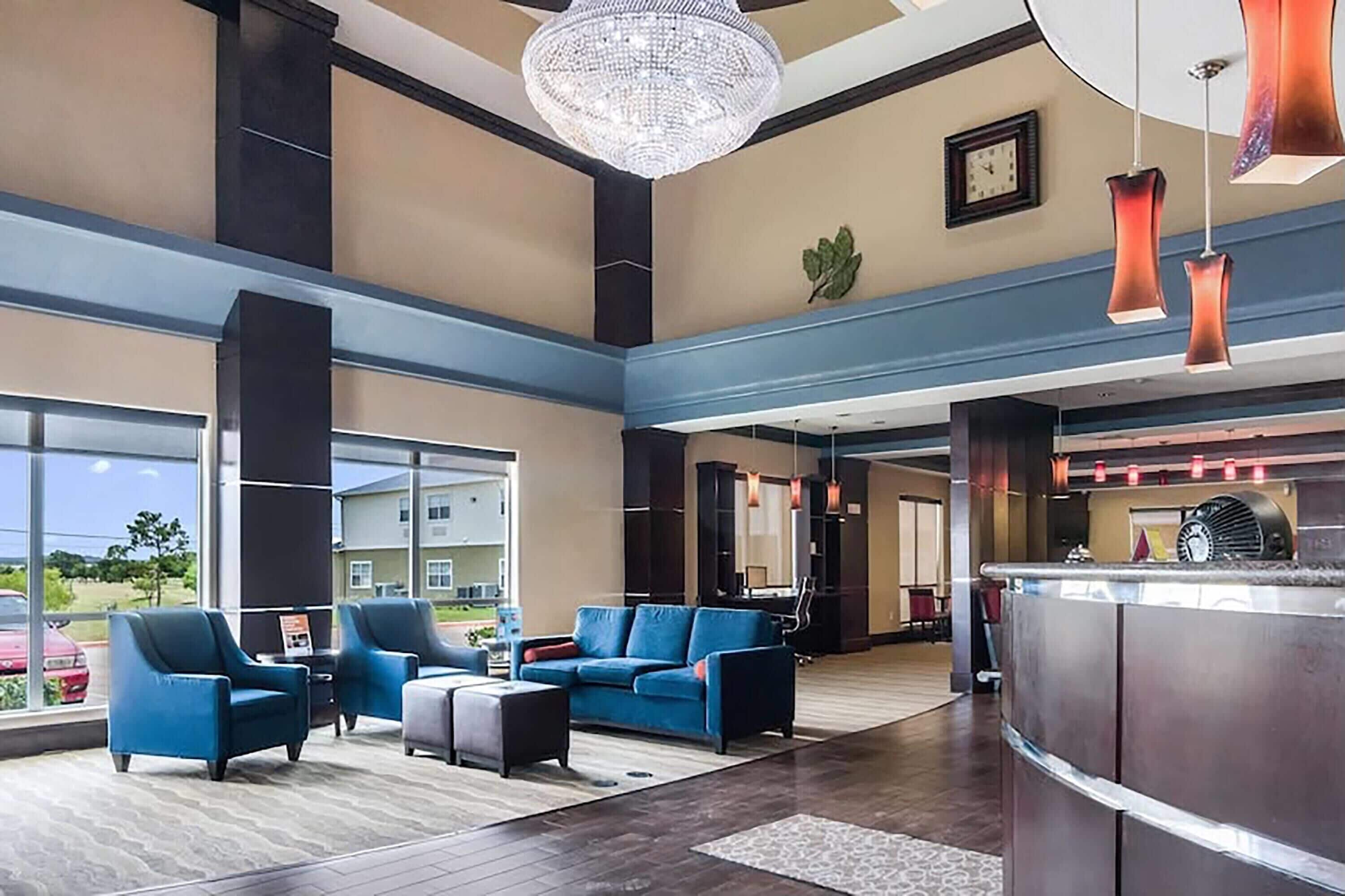 Eine geräumige Lobby mit einer Rezeption, einer blauen Sitzecke und großen Fenstern mit Blick ins Freie.