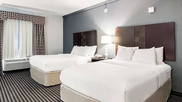 Una habitación de hotel con dos camas, una ventana con cortinas, una mesita de noche con lámpara y un radiador.