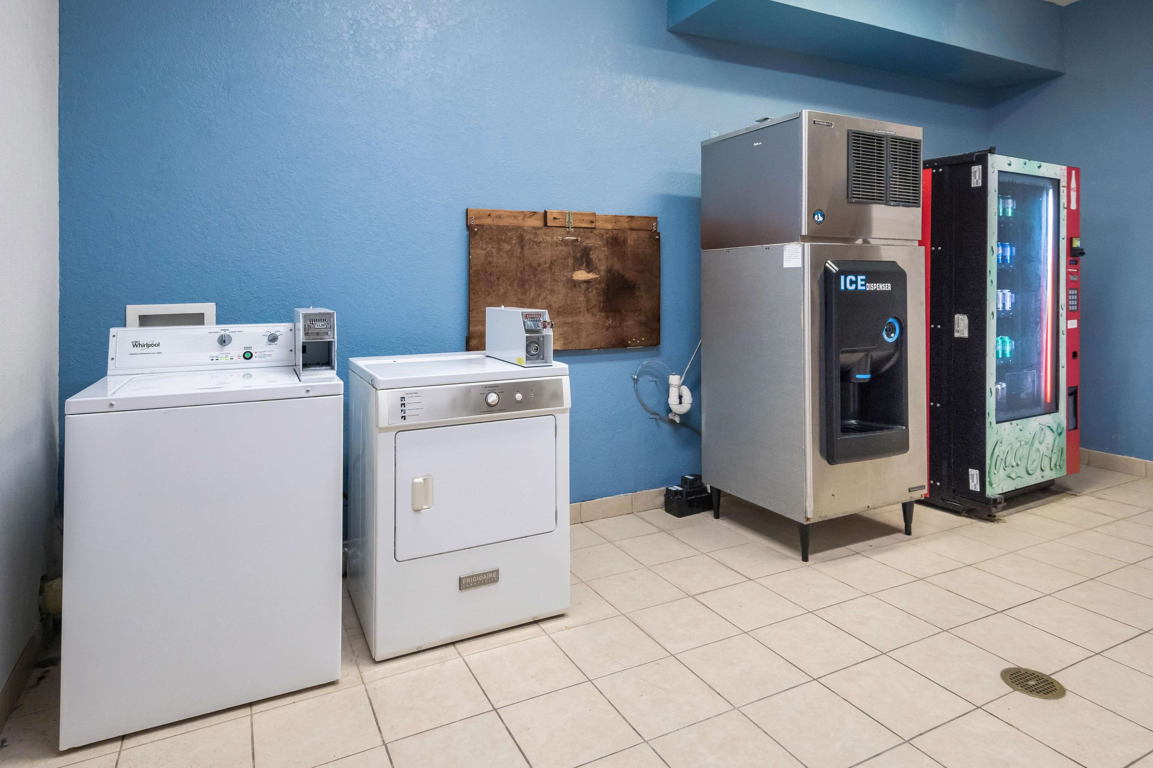 A laundry area with a Whirlpool washer, a Frigidaire dryer, an ICE dispenser, and a Coca-Cola refrigerator.