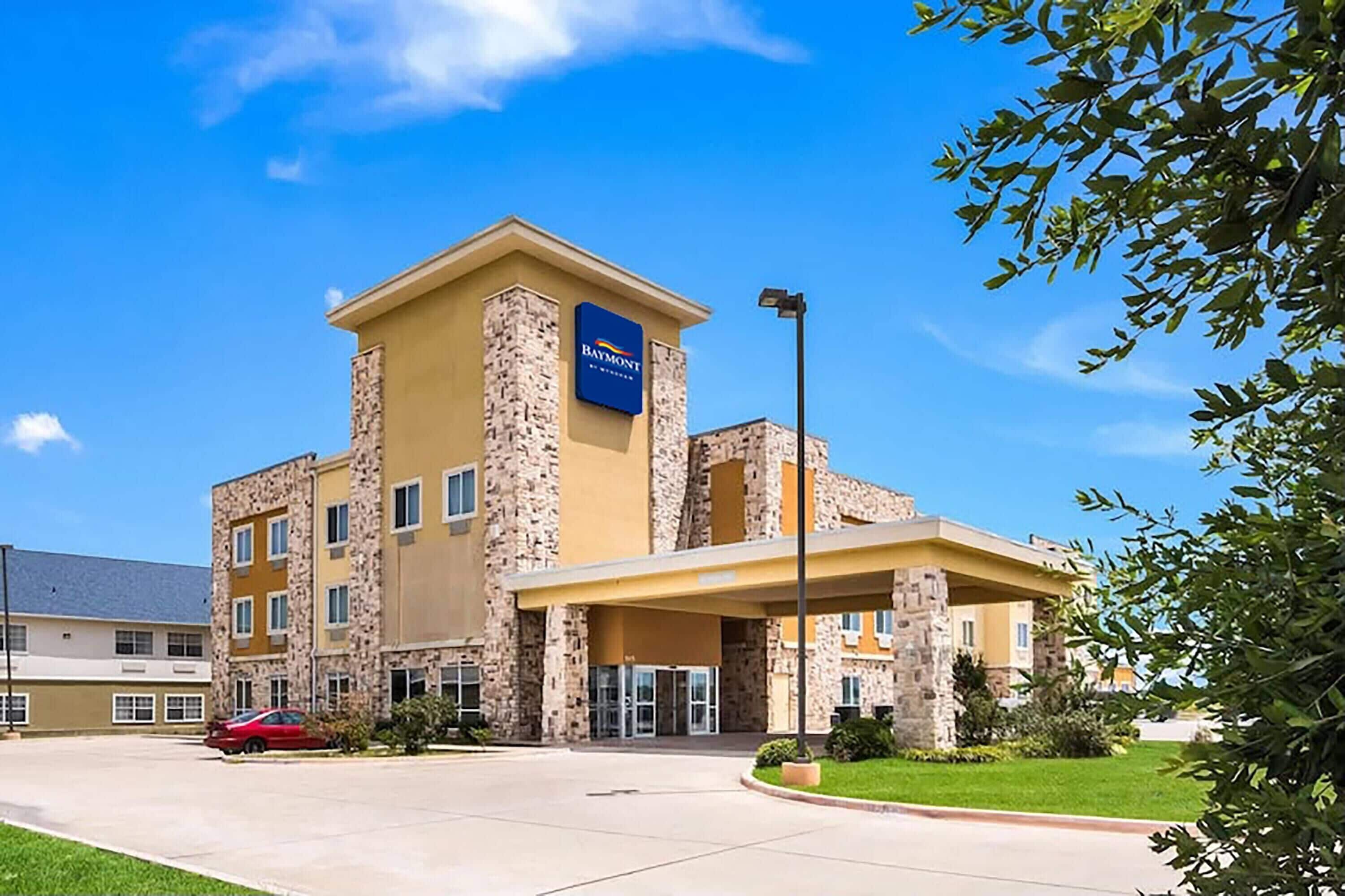 A multi-story hotel with a stone facade, a prominent sign, and a covered entrance.