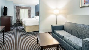 A hotel room with a bed, a sofa, a TV, and a lamp. - Baymont by Wyndham Mineral Wells (Mineral Wells)