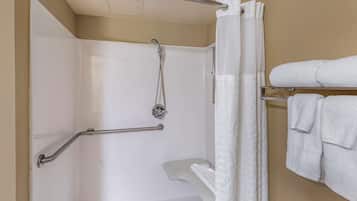 A shower area with a grab bar, a showerhead, and a towel rack with towels.