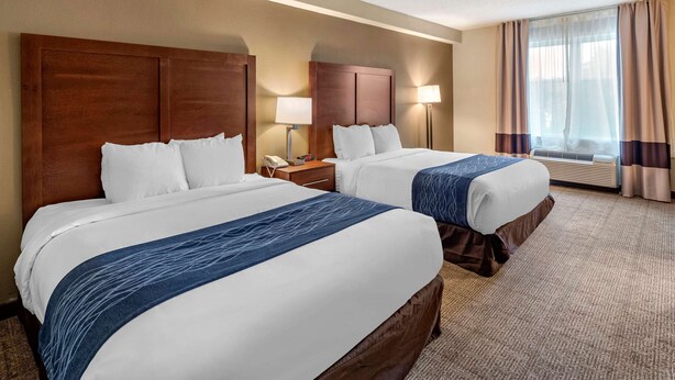 A hotel room with two beds, a nightstand with a phone, a lamp, and a window with curtains. - Comfort Inn & Suites Virginia Beach - Norfolk Airport (Virginia Beach)