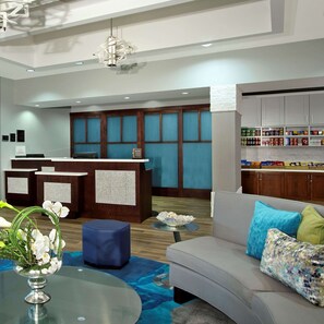 A modern lobby with a reception desk, seating area, and a display of snacks.