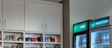 Zona de venta con aperitivos y bebidas, incluyendo un cartel que dice 'Really Cold' sobre el refrigerador.