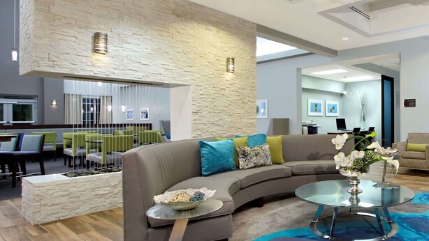 Ein modernes Wohnzimmer mit einem Ecksofa, einem Glastisch und einer Wand mit Steinverkleidung.