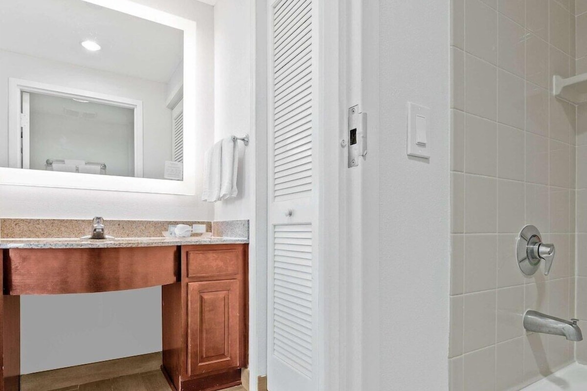 Une salle de bain équipée d’un lavabo, d’un miroir, d’un porte-serviettes et d’un espace douche.