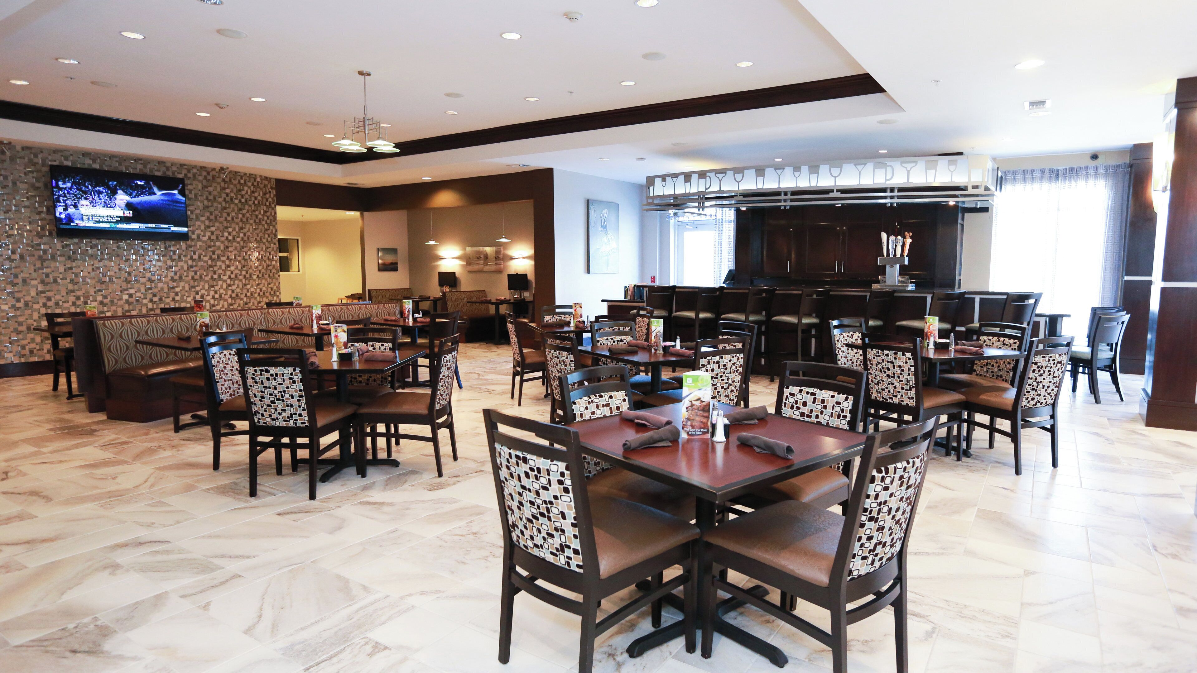 A restaurant with booths and tables, a TV mounted on the wall, and a bar area.