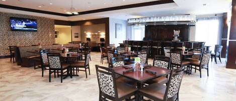 A restaurant with booths and tables, a TV mounted on the wall, and a bar area.
