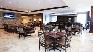 A restaurant with booths and tables, a TV mounted on the wall, and a bar area. - Holiday Inn Houston Webster by IHG (Webster)