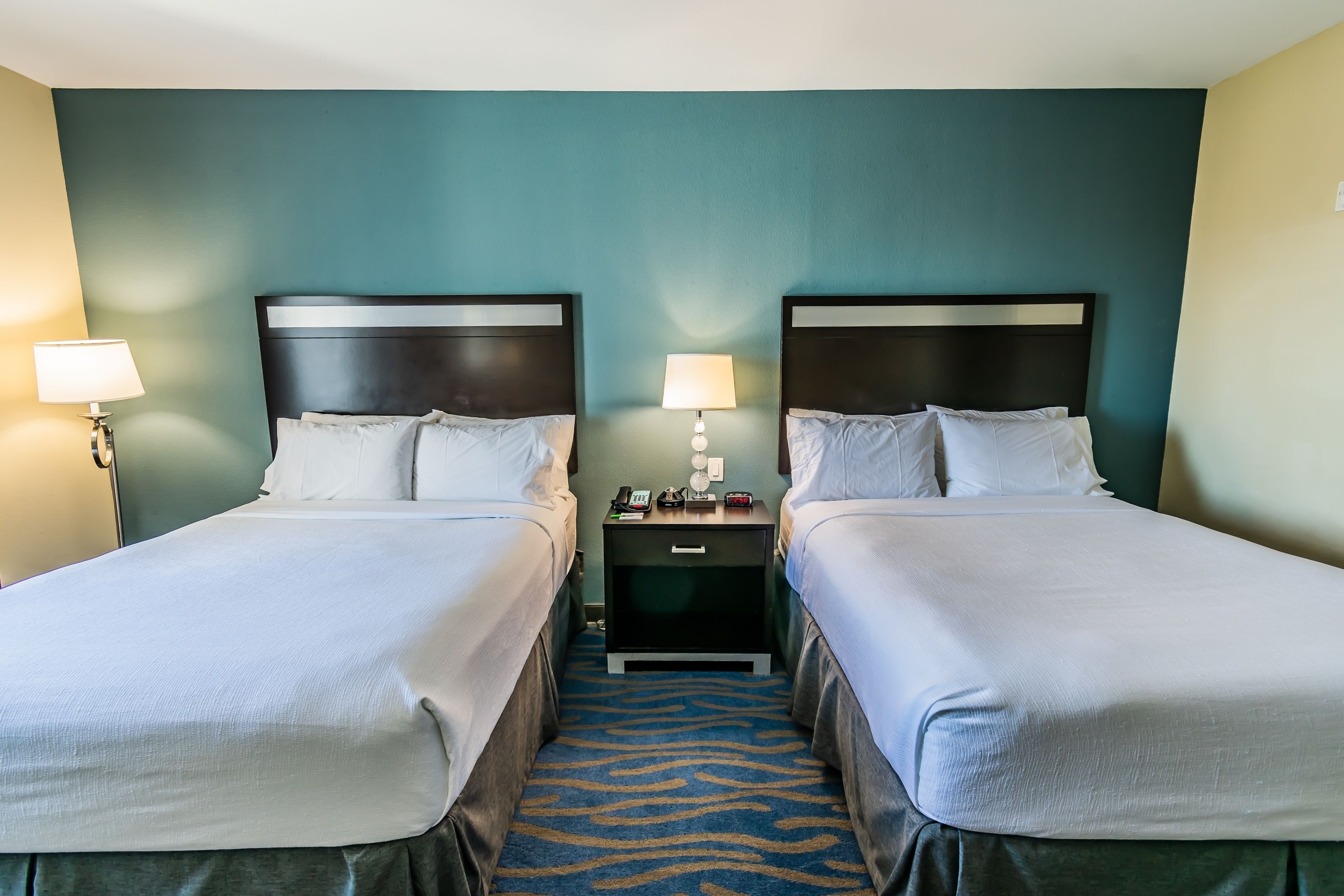 A hotel room with two beds, a zebra-patterned carpet, and bedside lamps.