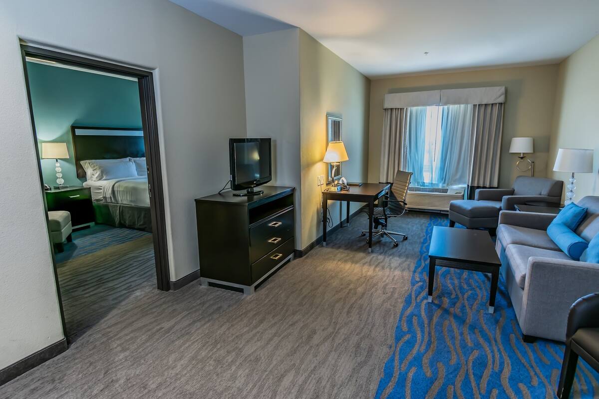 A hotel room with a bed, a desk, a television, a sofa, and a coffee table.