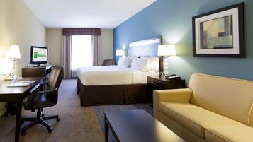 A hotel room with a bed, desk, chair, and a couch.