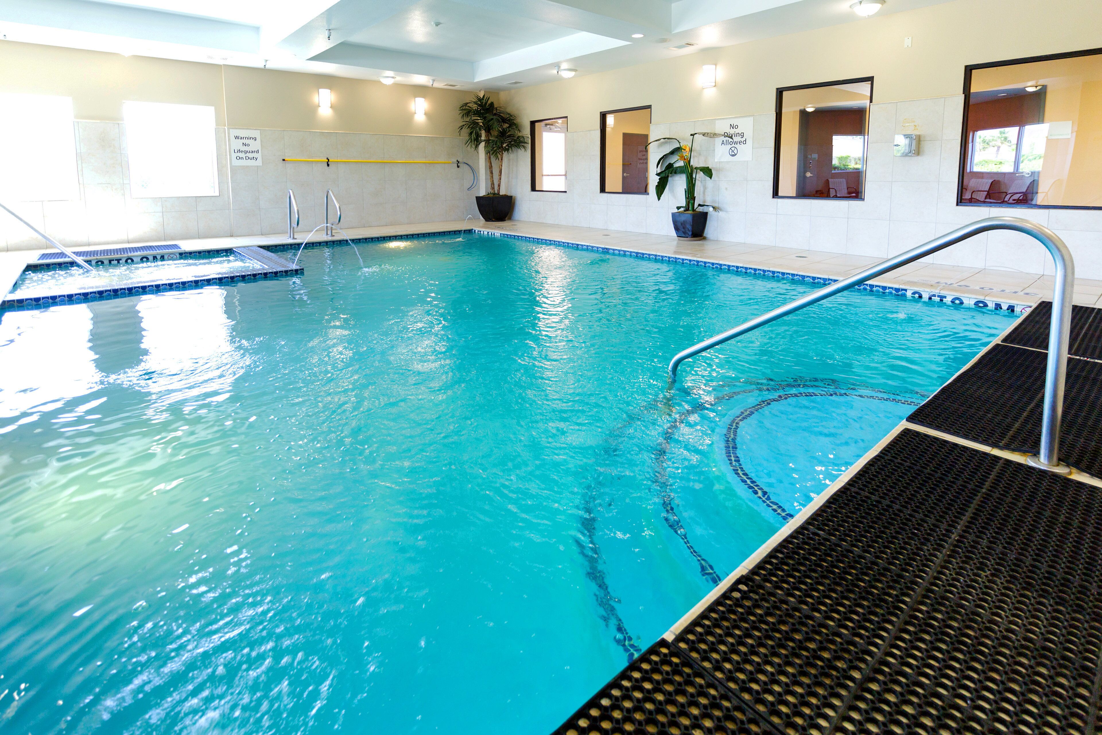 An indoor swimming pool with clear water, a diving board, and a lifeguard stand.