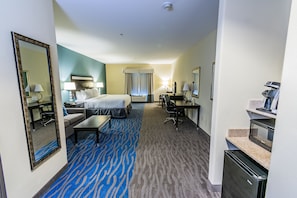 A hotel room with a bed, a desk, a chair, a sofa, a coffee machine, and a microwave. - Holiday Inn Houston Webster by IHG (Webster)