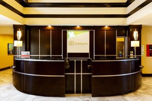 A hotel reception desk with a digital screen displaying the hotel name, a check-in counter, and a reception area with a marble floor. - Holiday Inn Houston Webster by IHG (Webster)