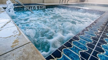 Un jacuzzi con piso de azulejos y escalera metálica.