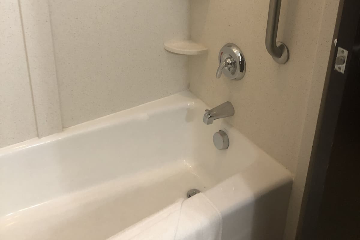 Une salle de bain standard équipée d’une baignoire, d’une barre d’appui et d’un porte-serviettes.
