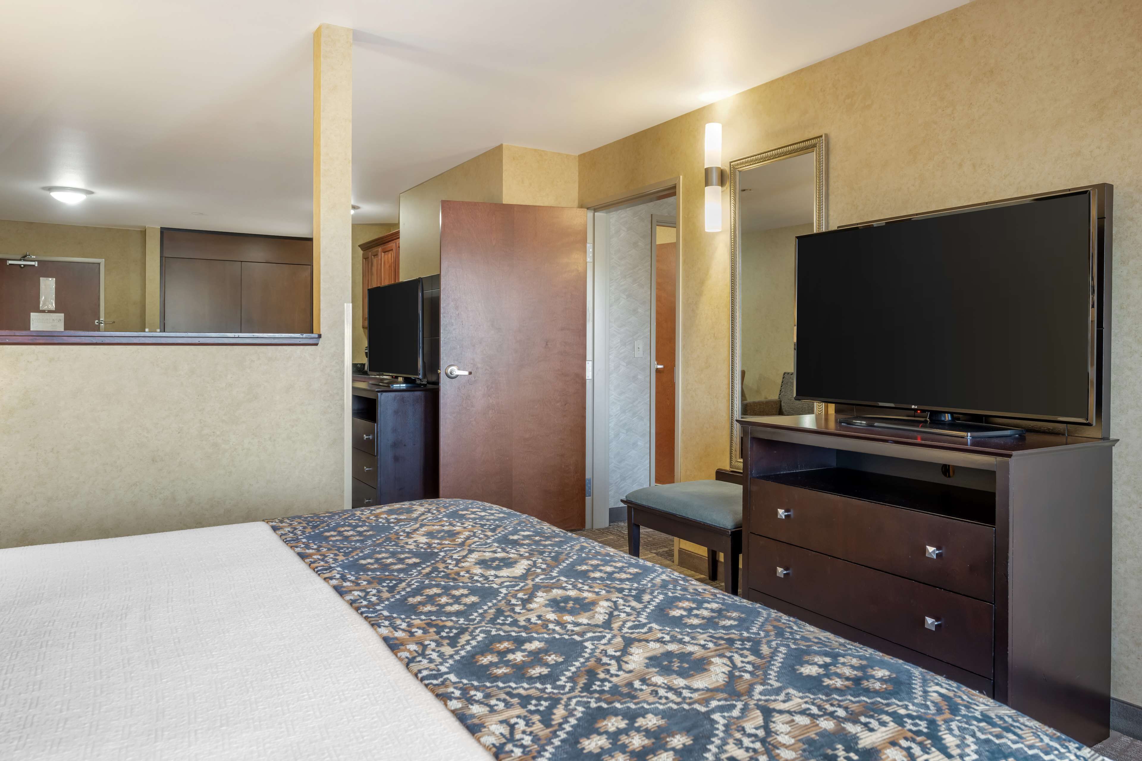 Een hotelkamer met een bed, een televisie, een dressoir en een spiegel.