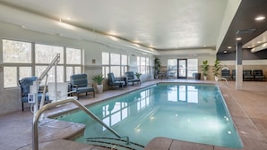 An indoor swimming pool with clear water, surrounded by lounge chairs and potted plants. - Best Western Plus Ponderay Mountain Lodge (Ponderay)