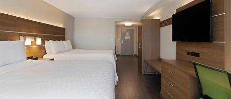 A hotel room with two beds, a desk, a chair, a television, and a door leading to a hallway.
