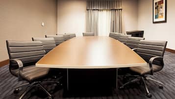 A conference room with a large oval table, multiple chairs, a small table, and a curtain.