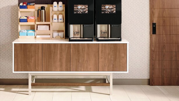 A wooden counter with storage compartments and two coffee machines.