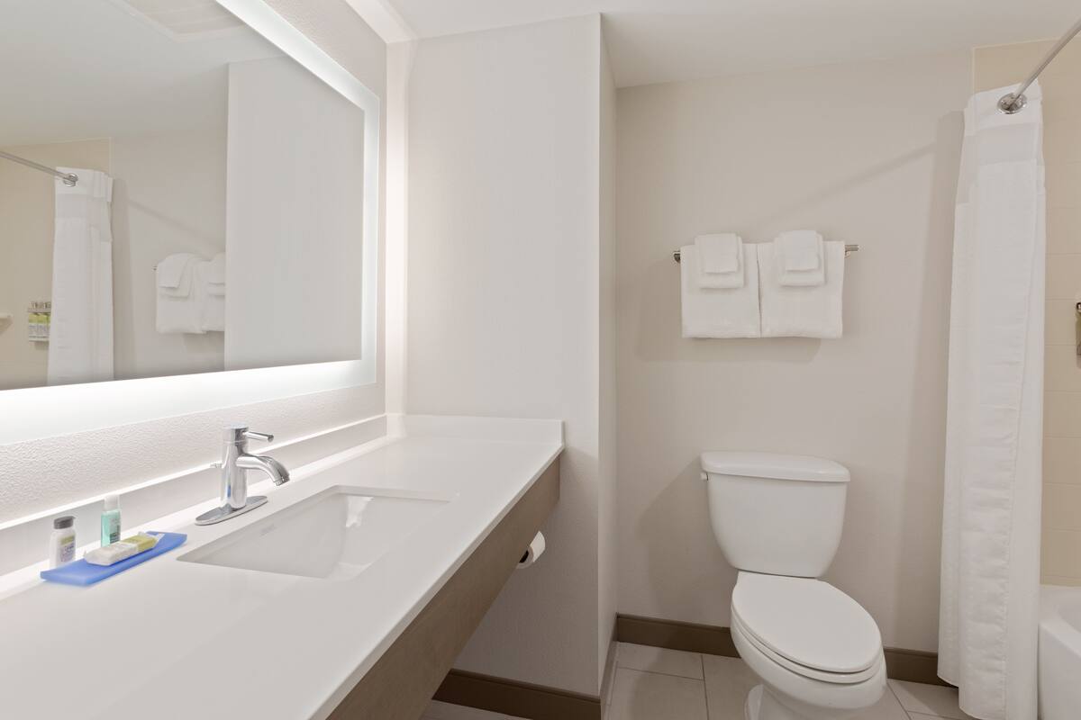 A modern bathroom with a white sink, mirror, and toilet.