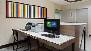 A hotel reception desk with a computer, printer, and chairs.