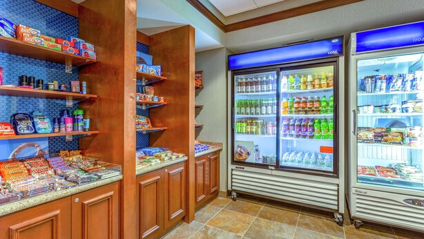 Un bar de aperitivos con estantes llenos de diferentes bocadillos y bebidas, y dos vitrinas refrigeradas con la etiqueta 'frío'.