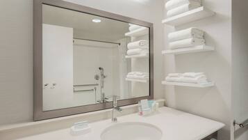 A modern bathroom with a large mirror, a sink, and built-in towel racks.