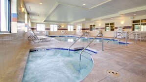 A large indoor swimming pool with multiple lanes, surrounded by lounge chairs and sun loungers.