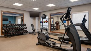 A gym with treadmills, a rowing machine, dumbbells, and exercise balls.