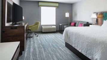 A hotel room with a bed, a desk, a chair, a television, a window with a view, and an air conditioning unit.