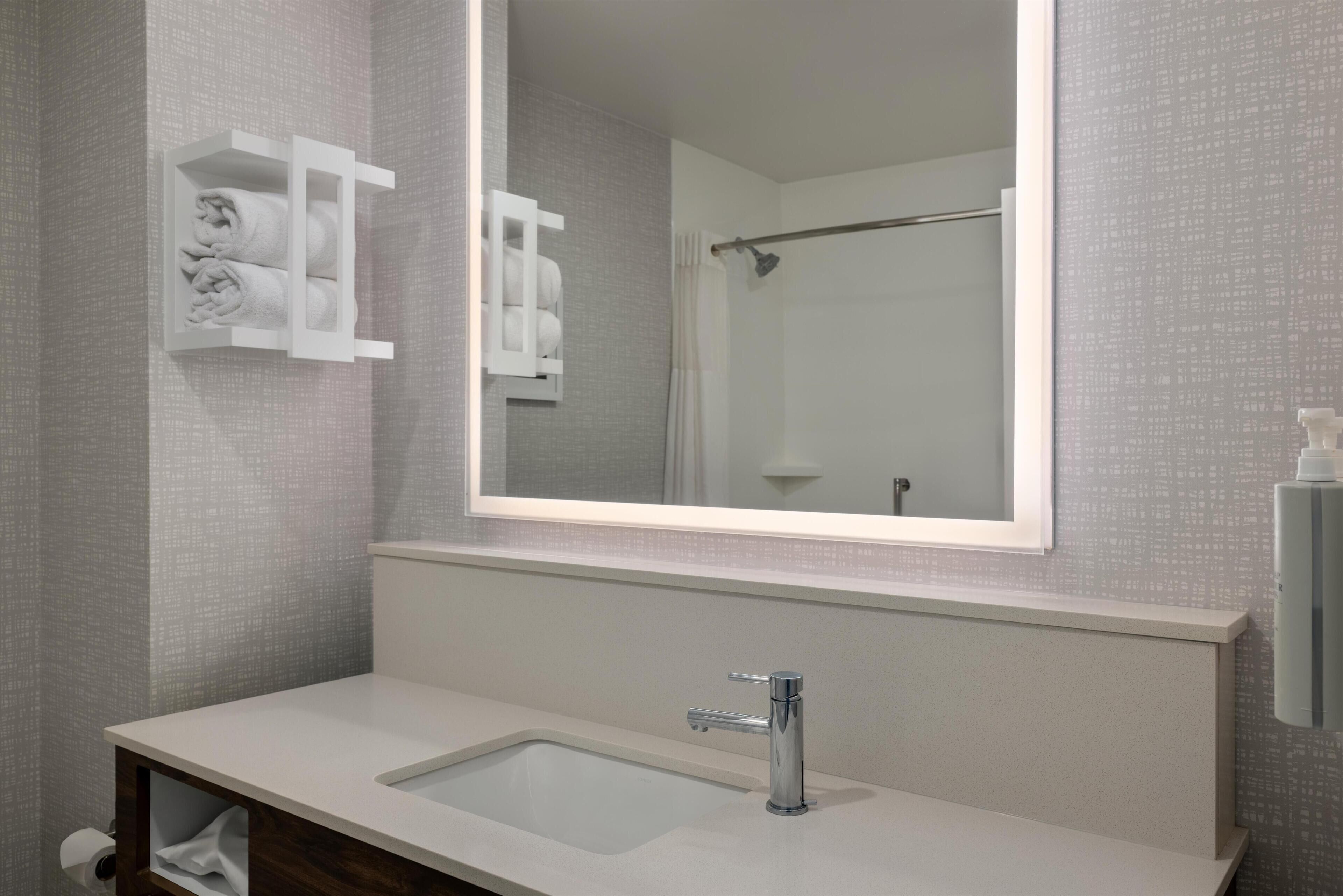 A bathroom with a white sink, a mirror, and a towel rack.