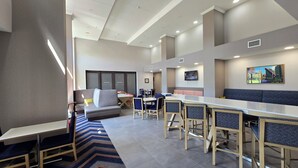 A modern hotel lobby with seating areas, a bar, and a staircase. - Hampton Inn & Suites Chicago Deer Park (Barrington)