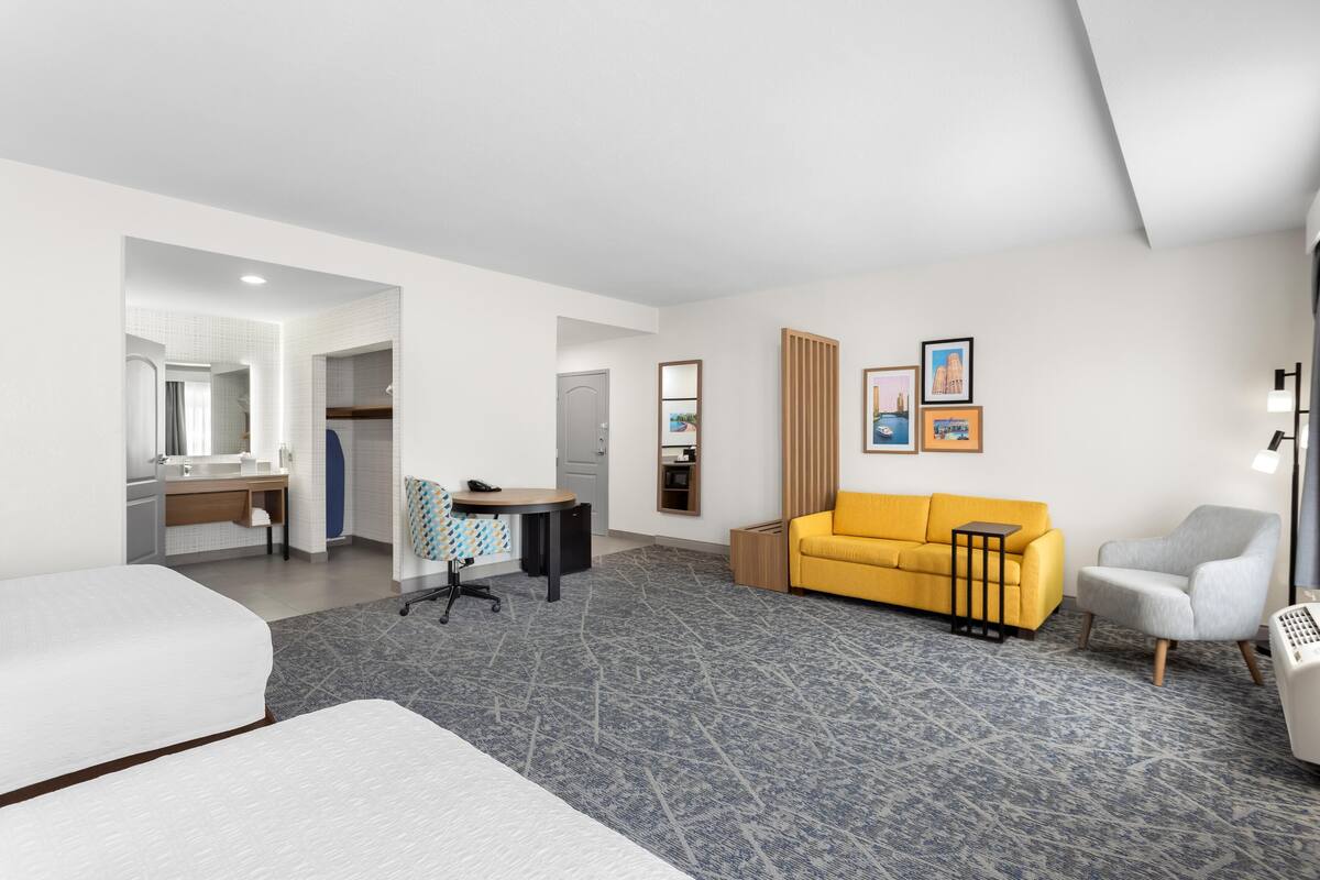 A hotel room with a bed, a desk, a sofa, and a chair.