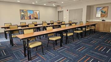 A conference room with a long table and chairs, carpeted floor, and artwork on the walls.