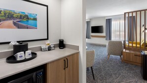 A hotel room with a bed, a TV, a desk with a coffee maker, a chair, and a window with curtains. - Hampton Inn & Suites Chicago Deer Park (Barrington)