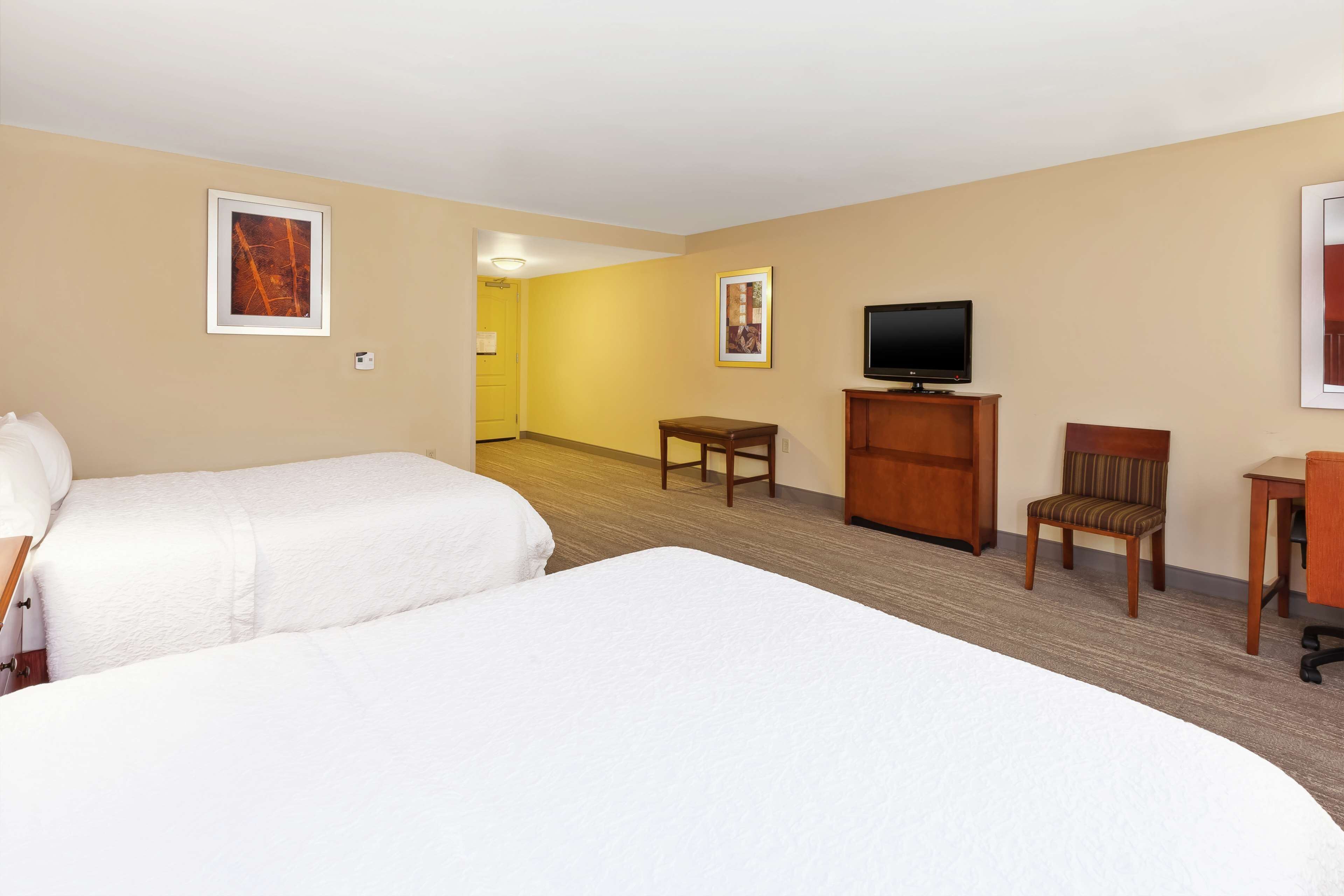 Une chambre d’hôtel avec deux lits, une télévision, un bureau et une chaise.